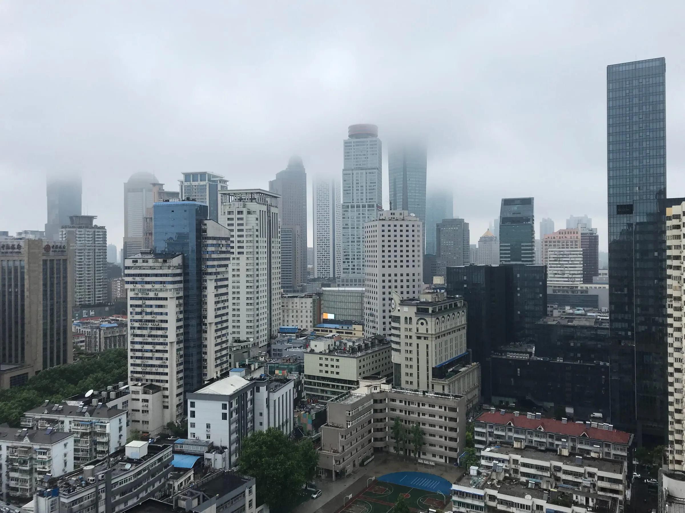 City towers from a high window, their tops disappearing into low cloud