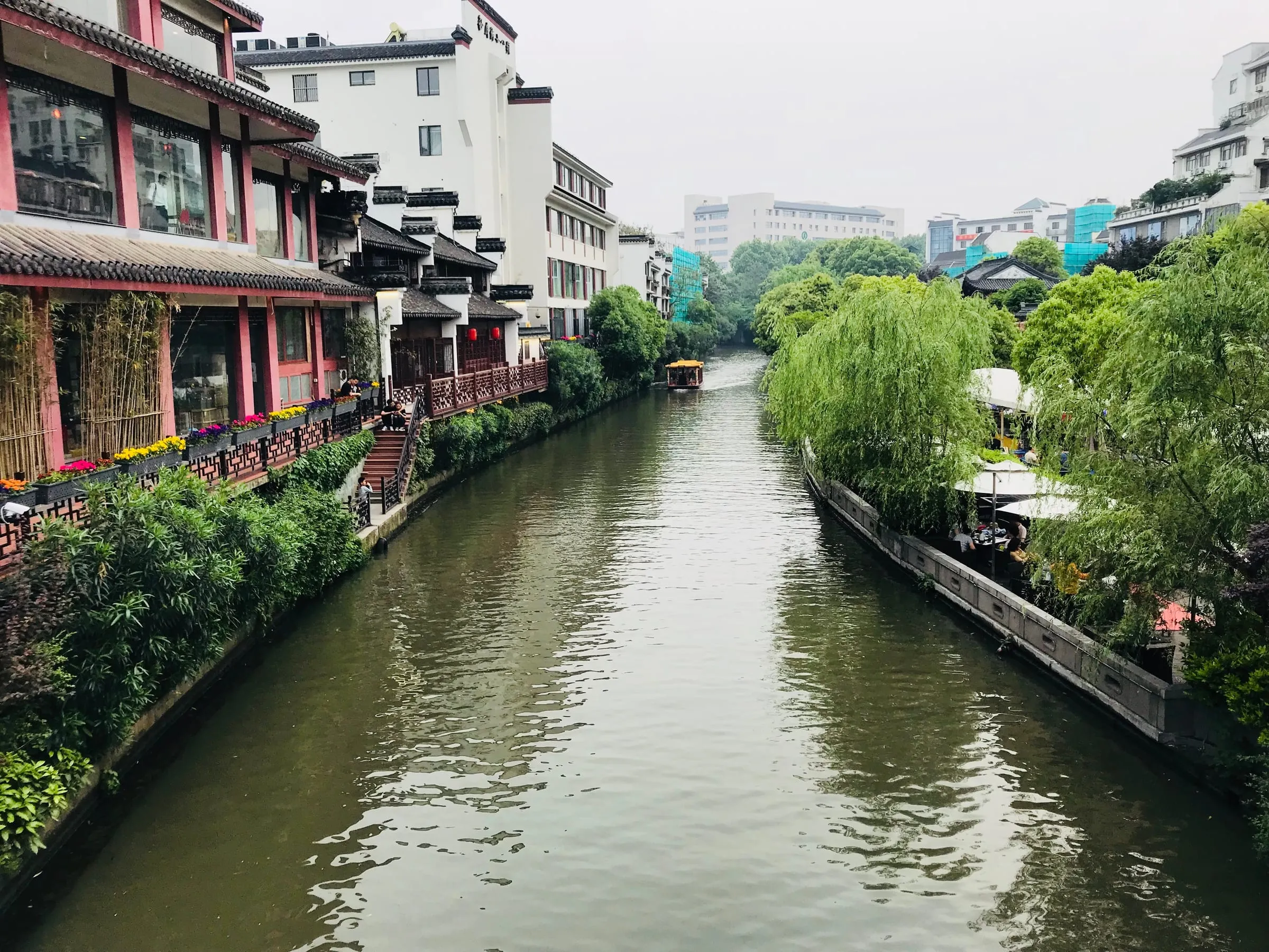 A quiet canal between old white houses and willow trees, the water still and green