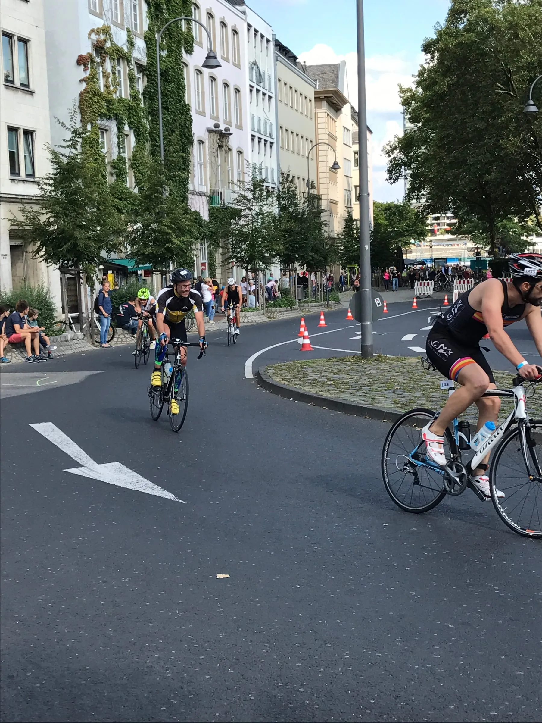 Cyclists racing round a bend on a closed city street, a white arrow painted on the road