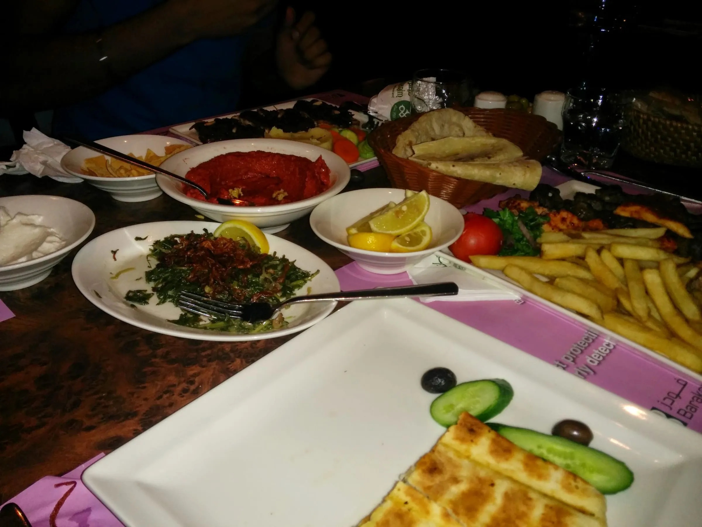 A dinner table crowded with plates of salad, bread, fries and dips