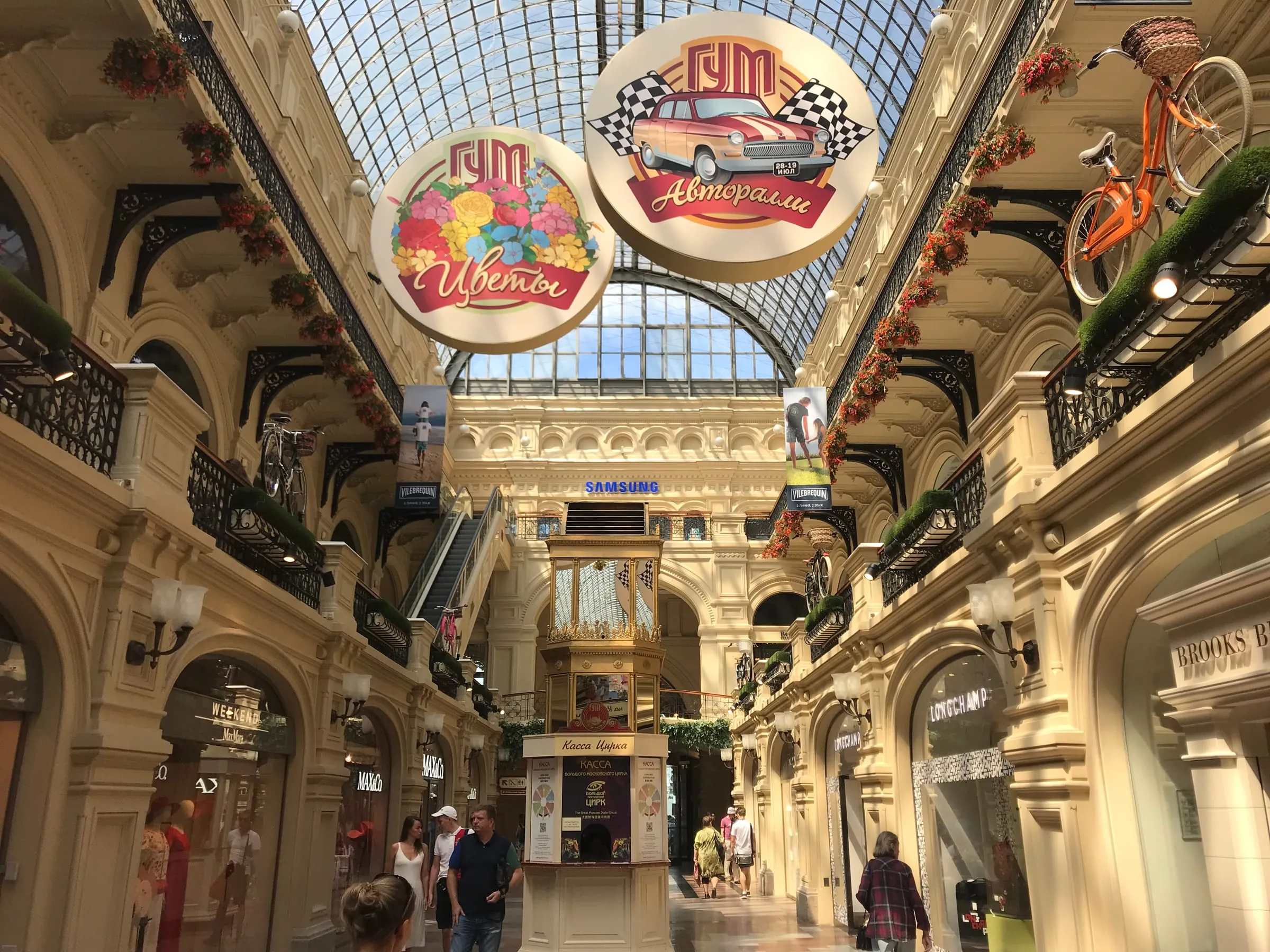 Inside GUM, a glass-roofed arcade with ornate balconies and round hanging signs