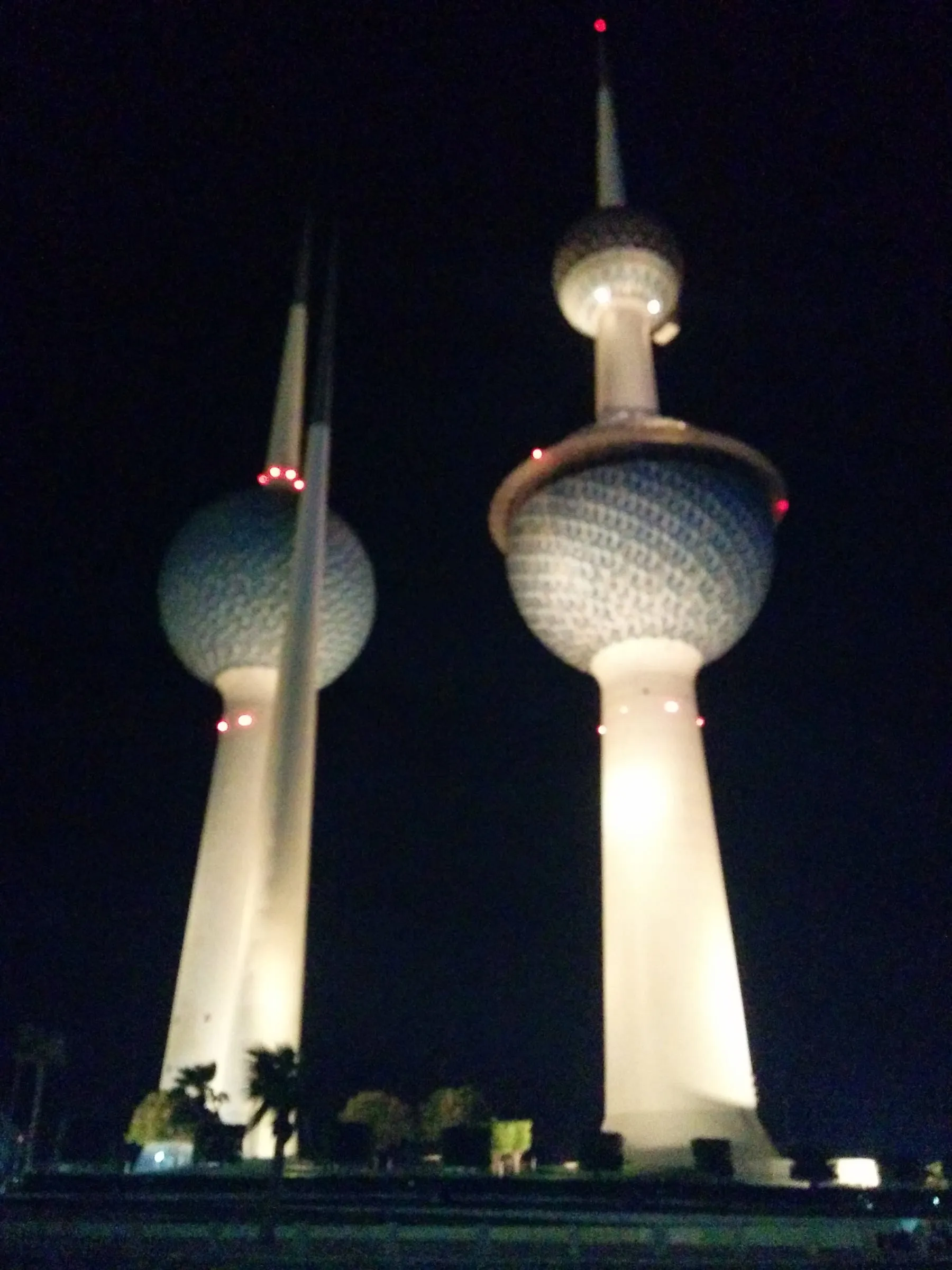 The Kuwait Towers lit white against a black night sky