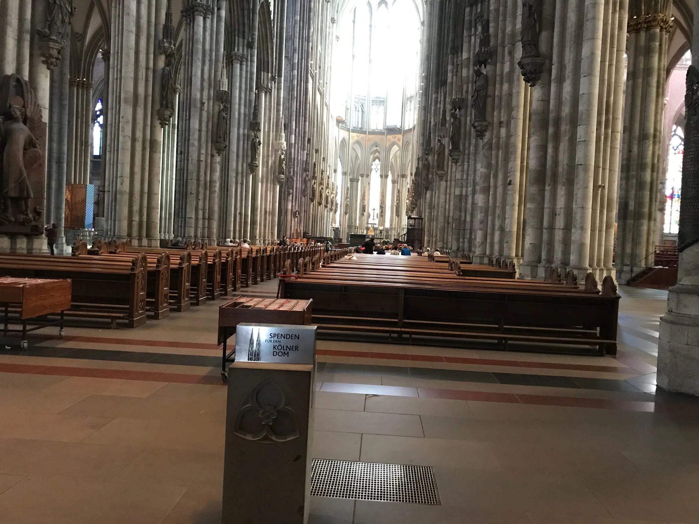 Inside the cathedral, rows of wooden pews between tall stone columns