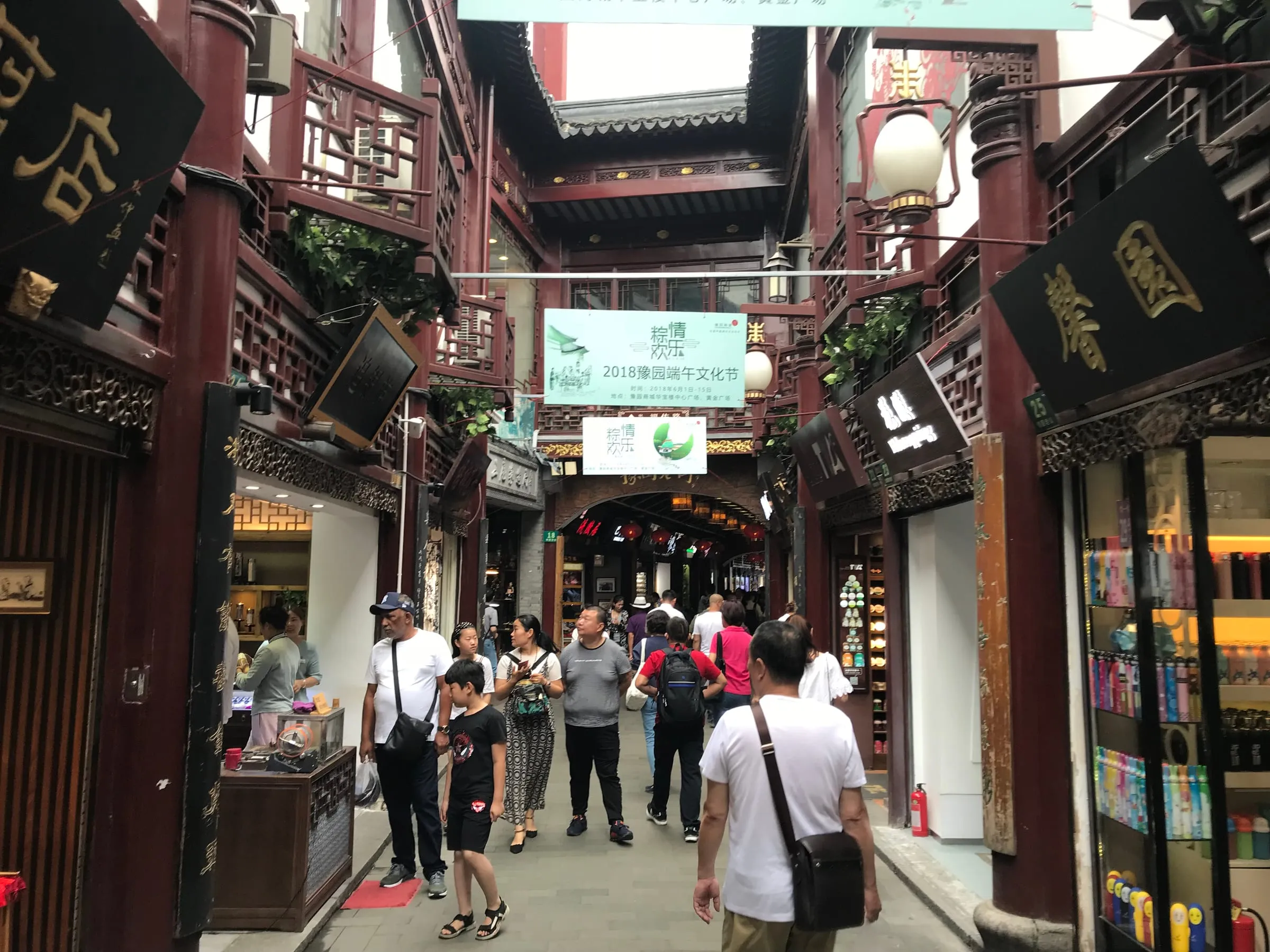 A busy old shopping street with dark wooden shopfronts and hanging signs