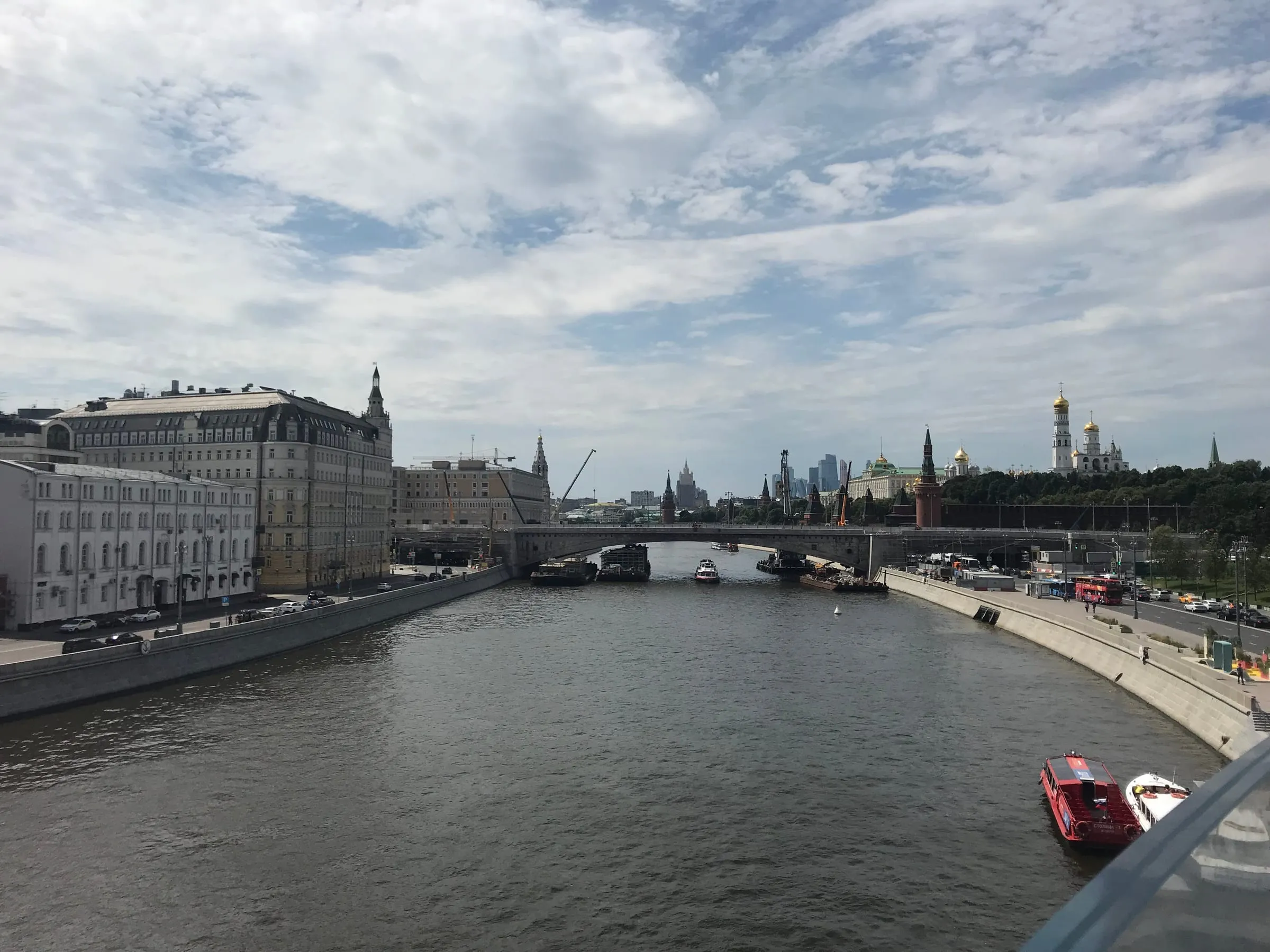 The Moskva river from a bridge, embankments on both sides and a bridge in the distance