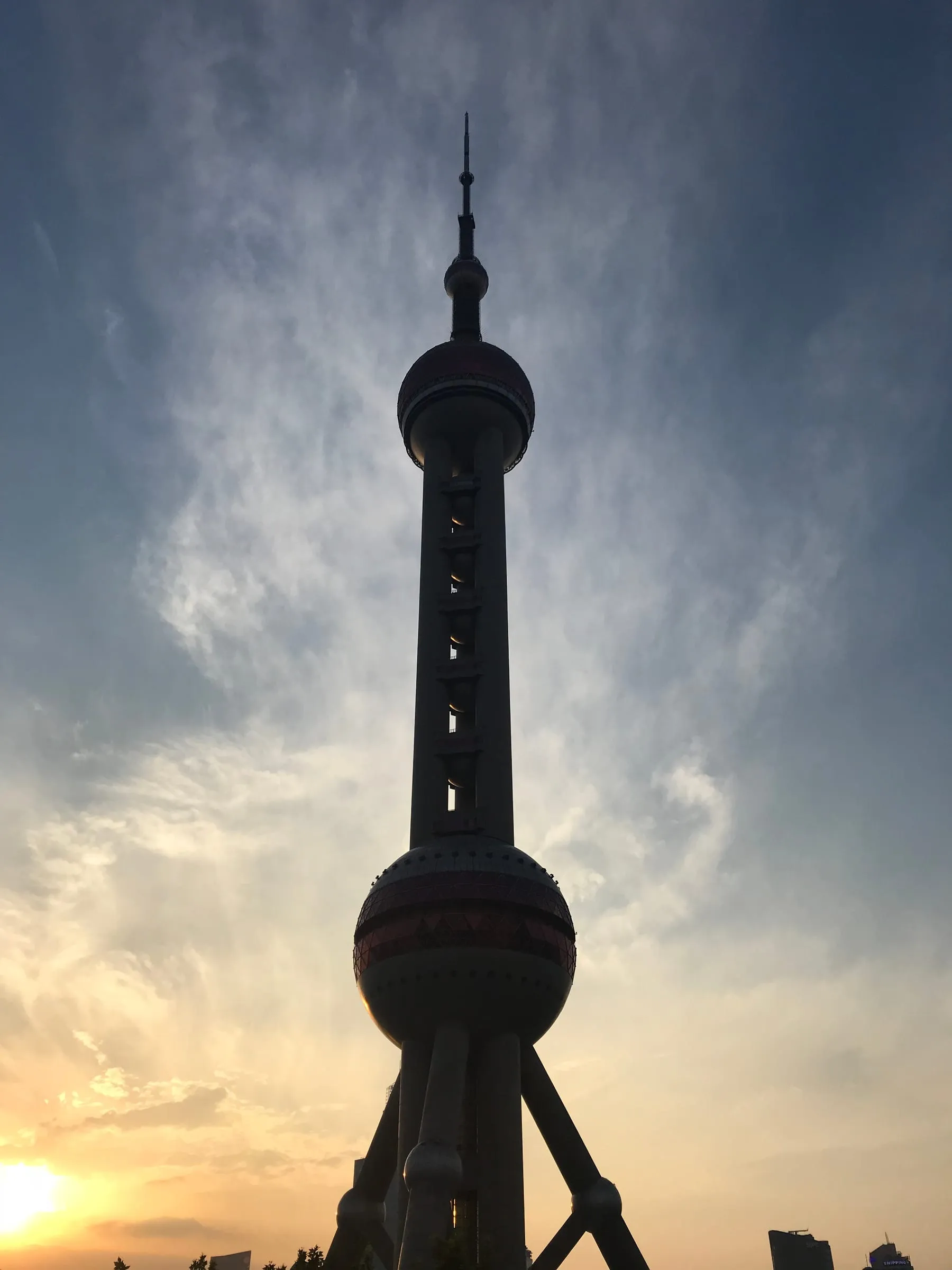 The Oriental Pearl Tower in silhouette against a sunset sky